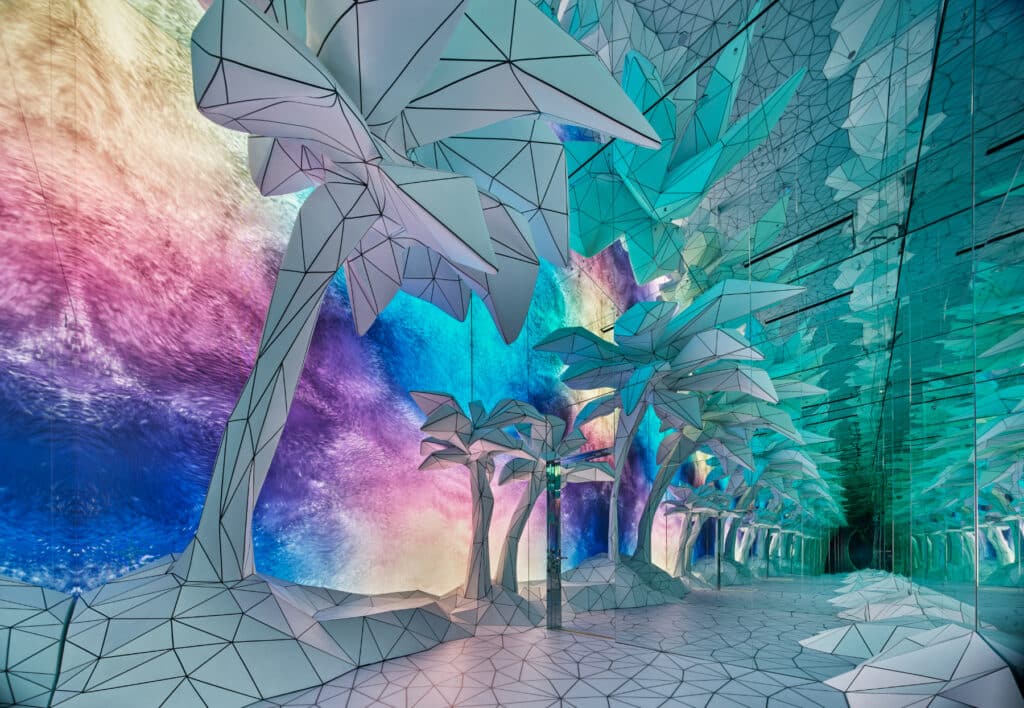 A futuristic room with geometric, origami-like palm trees, reflective floors and ceiling, and vibrant, multicolored walls creating a surreal, dreamlike atmosphere.