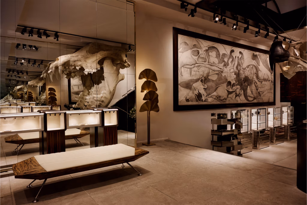 A modern gallery space with a large animal skull, mirrored walls, display cases, a bench, and a framed paleontological mural featuring dinosaur skeletons. Soft lighting highlights the art and displays.